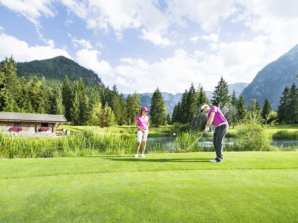 Wandern am Achensee: traumhaft schön Zwei Golfer in pinken Hemden spielen auf einem Golfplatz mit Bergkulisse