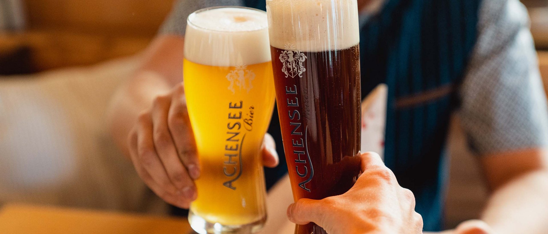 Feiern, Staunen und Genießen Zwei Personen stoßen mit einem hellen und einem dunklen Achensee Bier an