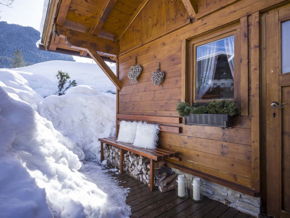 Hotel on Lake Achensee? The Karlwirt! Wooden bench with white pillows outside a snow-covered mountain cabin