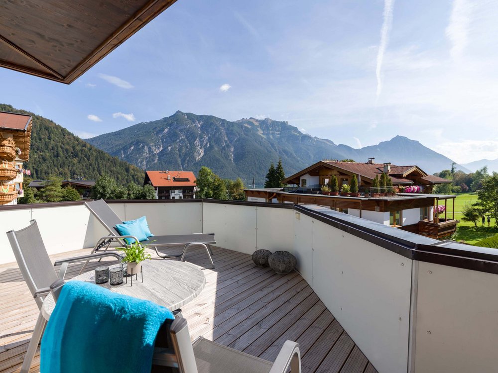 4-star hotel on Lake Achensee in Pertisau Balcony with lounge chairs and mountain view on a sunny day