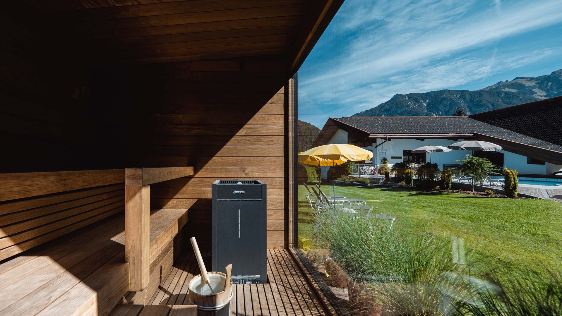 Wellnesshotel am Achensee: Karlwirt Sauna innen mit Holzbank und Blick durch Glas auf Garten und Berge