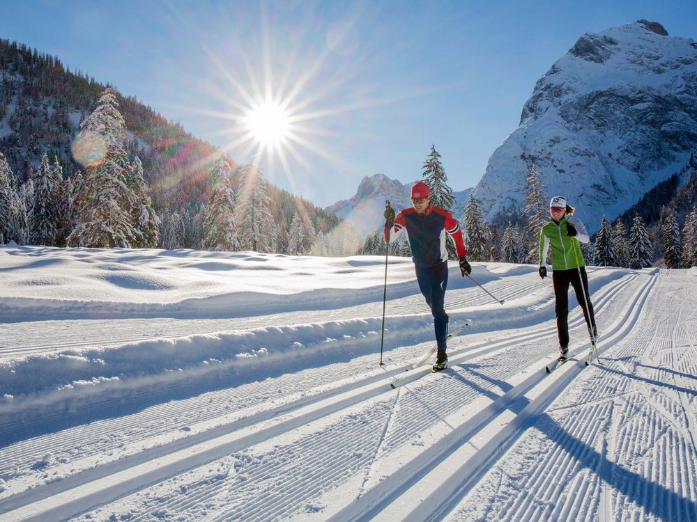 Achensee: Ausflugsziele und mehr Zwei Personen beim Langlaufen auf sonniger Winterloipe in den Bergen