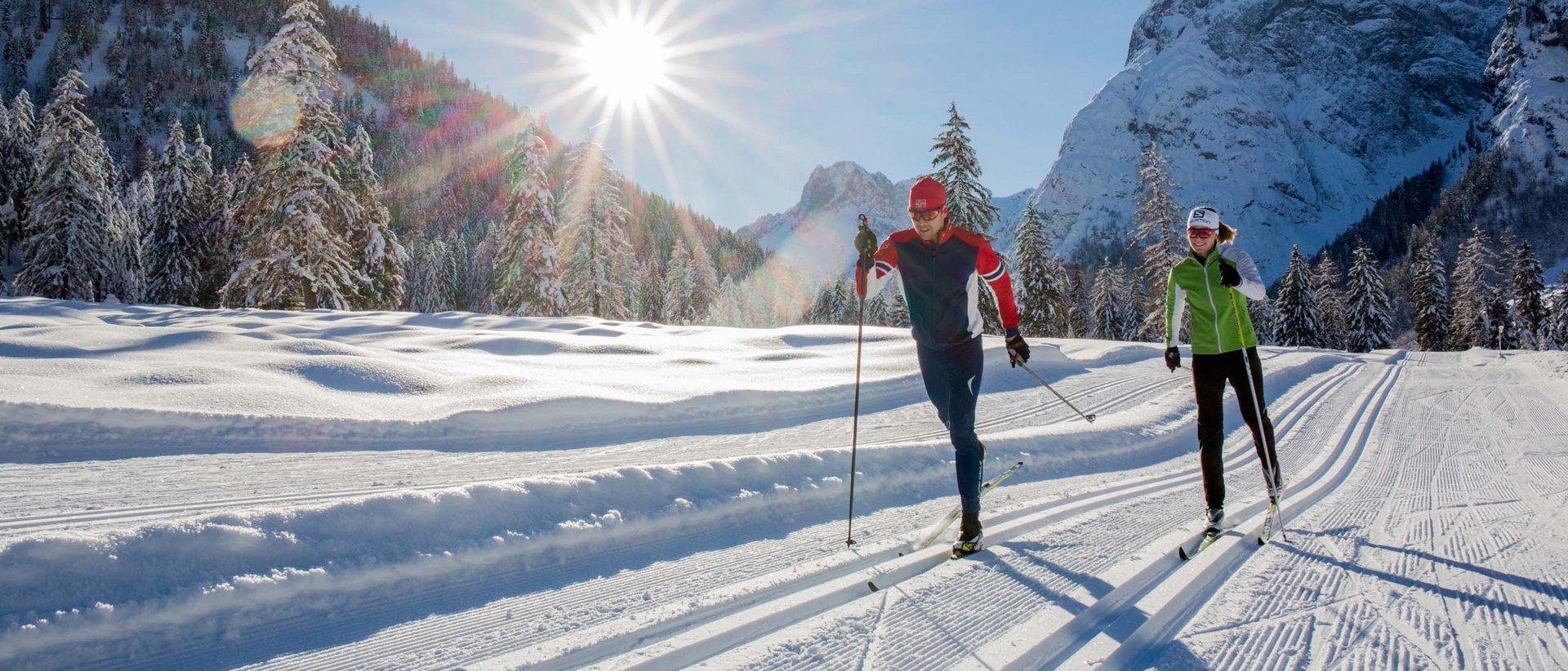 Ein unvergessliches Erlebnis Zwei Personen beim Langlaufen auf sonniger Winterloipe in den Bergen
