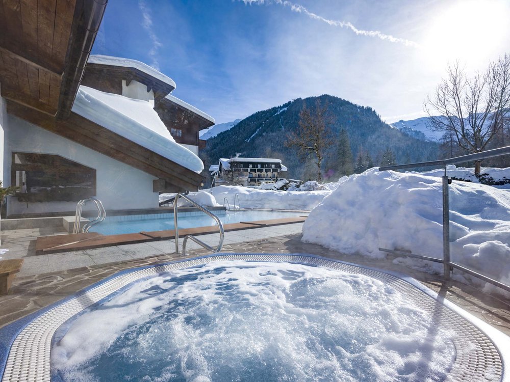 Lake Achensee + hotel with pool = Karlwirt Outdoor hot tub and pool beside snow-covered house with snowy mountain views