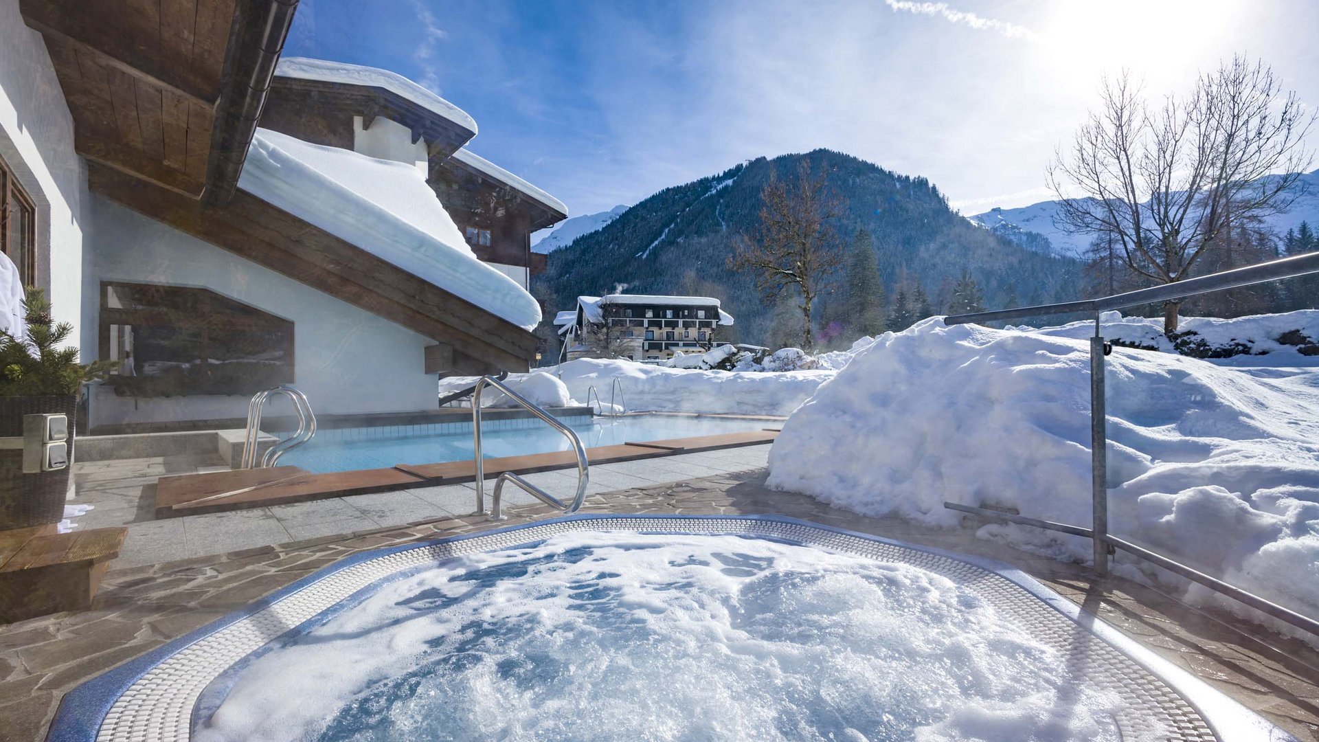 Lake Achensee + hotel with pool = Karlwirt Outdoor hot tub and pool beside snow-covered house with snowy mountain views