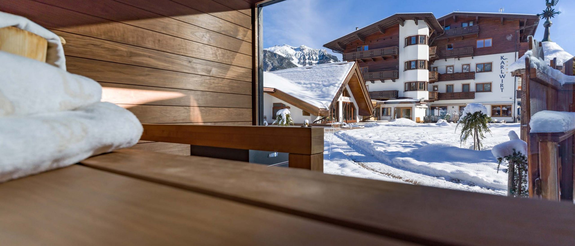 Entspannter Winterurlaub Blick aus Sauna auf verschneiten Hotelgarten und Berge bei Sonnenschein
