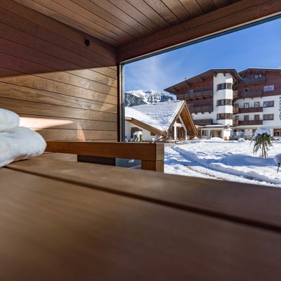 Verwöhnhotel am Achensee: Neuigkeiten Blick aus Sauna auf verschneiten Hotelgarten und Berge bei Sonnenschein