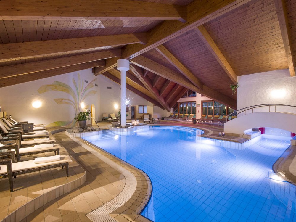 Wellnesshotel am Achensee: Karlwirt Innenpool mit Liegestühlen unter einer Holzdecke in einem Wellnessbereich