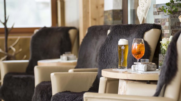 Das Hotel Karlwirt: herzlich willkommen! Gemütliche Sitzecke mit zwei Getränken auf Holztisch in Alpenstil