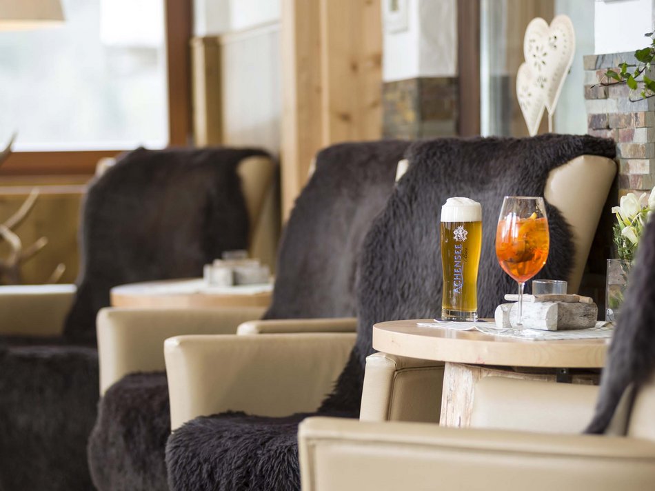 Das Hotel Karlwirt: herzlich willkommen! Gemütliche Sitzecke mit zwei Getränken auf Holztisch in Alpenstil