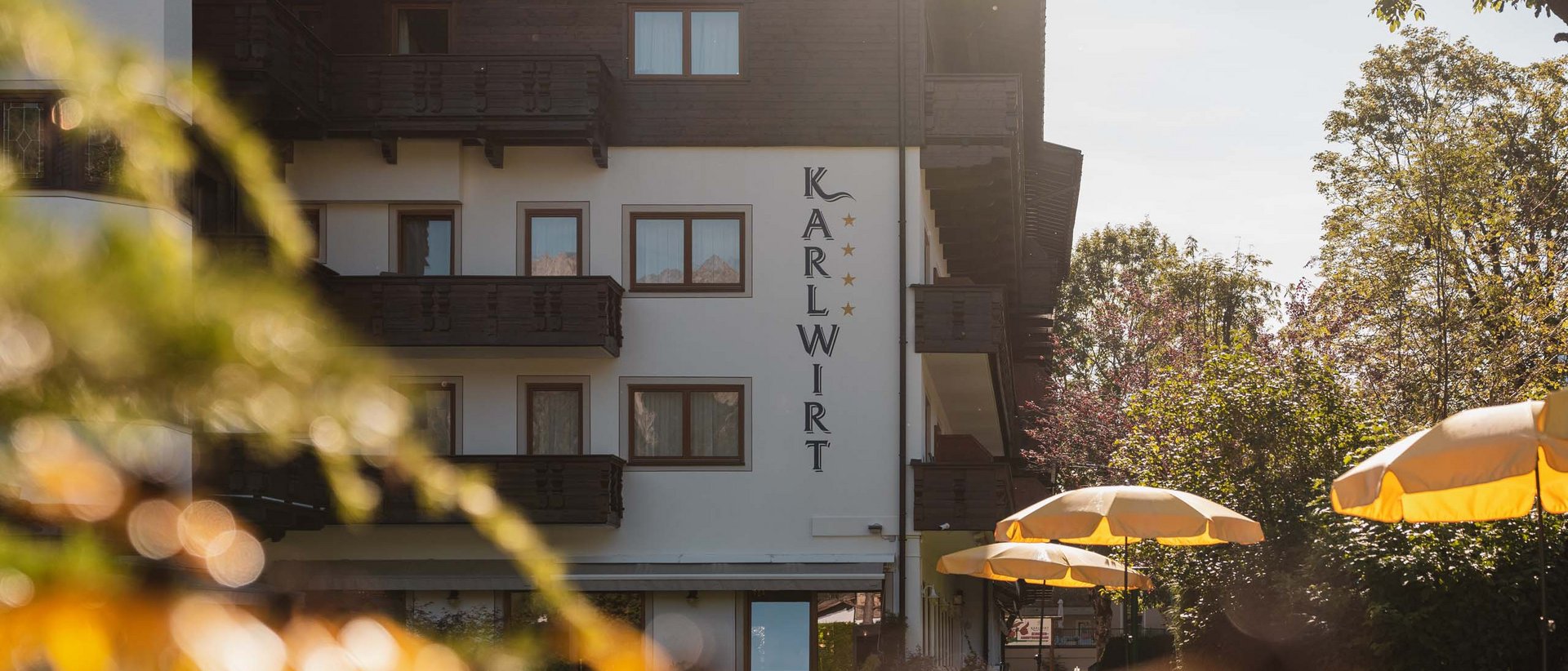 Entspannung pur im Hotel Karlwirt Hotel Karlwirt mit Sonnenschirmen und Bäumen im Sonnenlicht