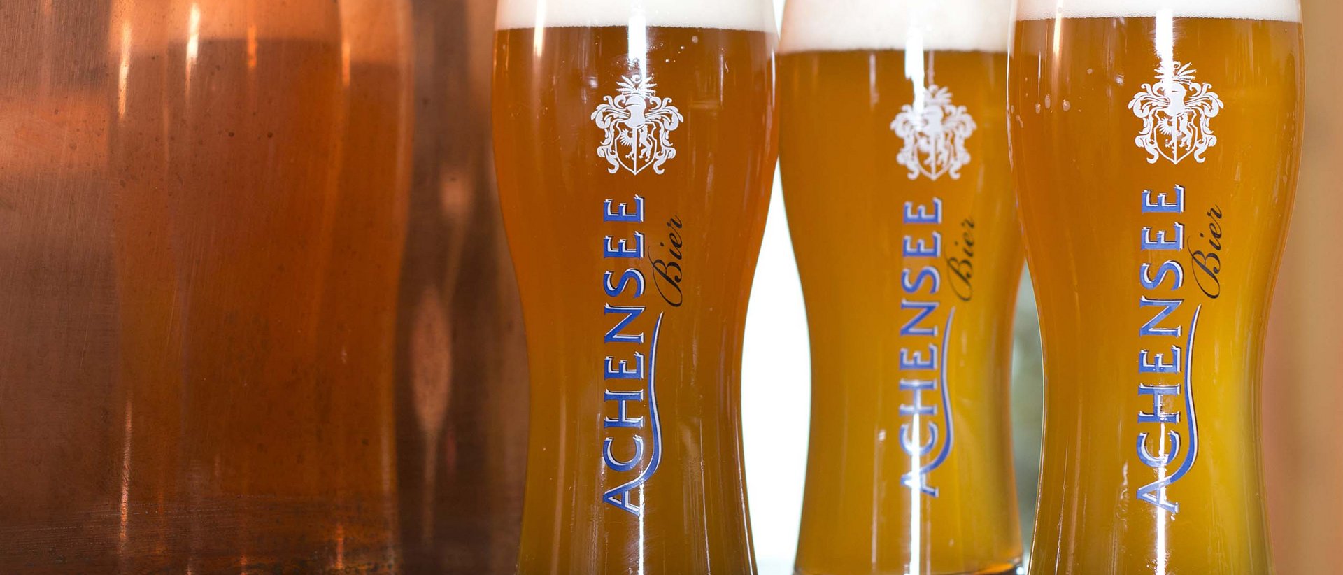 Eine bierige Zeitreise Drei Gläser Achensee Bier mit Schaum auf einem Tisch vor Kupferwand