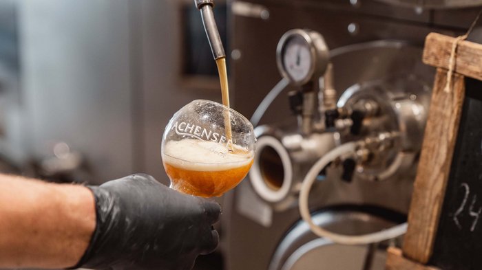 Das Achenseebier des Karlwirt Bier wird aus einem Hahn in ein Achensee Bierglas eingeschenkt