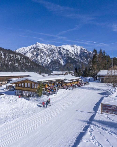 Hotel on Lake Achensee? The Karlwirt! Winter landscape with snow-covered mountains and ski lodge with people on sunny terrace