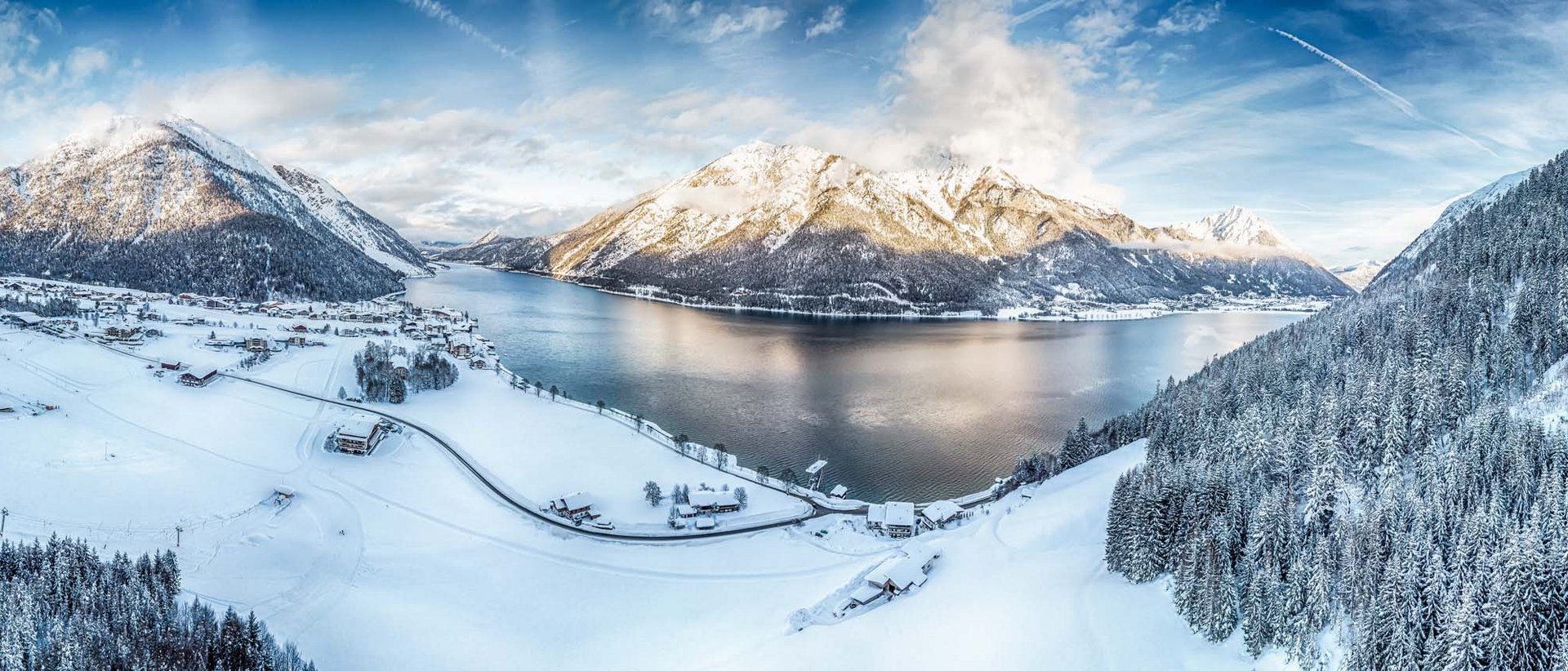 So gelingt der Einstieg bestimmt Winterlandschaft mit schneebedecktem Dorf und Bergsee unter blauem Himmel