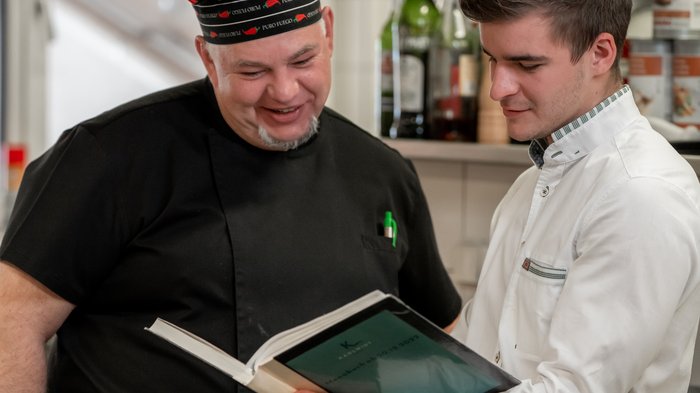 Hotel in Pertisau/Lake Achensee: join us! Two men in a kitchen looking at a book together