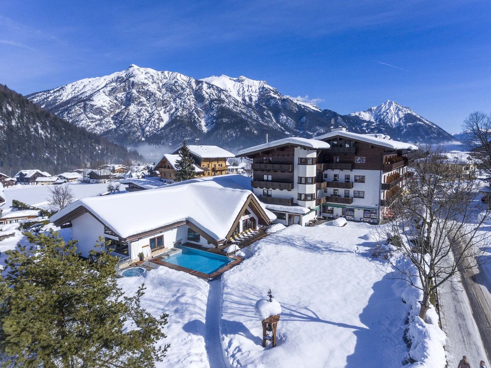The Karlwirt on Lake Achensee: our history Snow-covered hotel with outdoor pool in Alpine mountain landscape