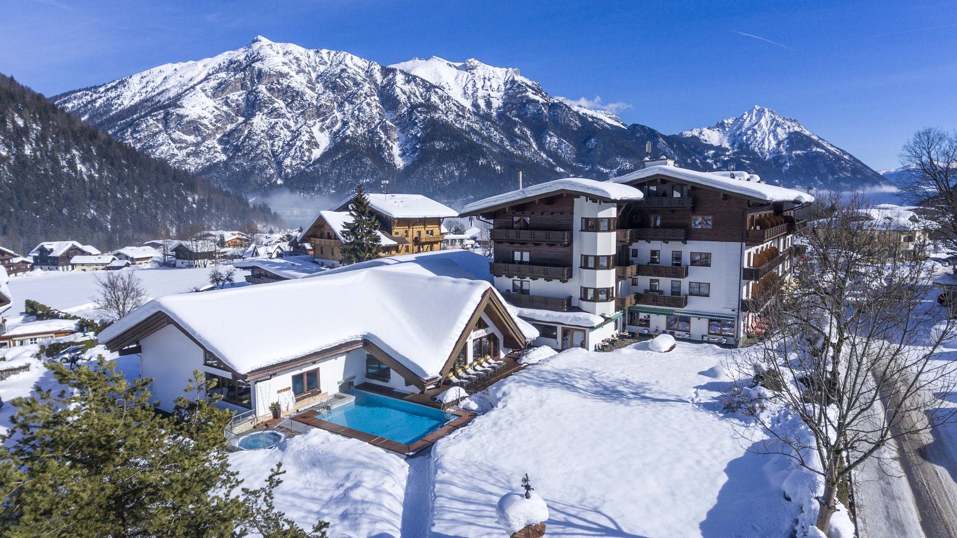 Snow-covered hotel with outdoor pool in Alpine mountain landscape