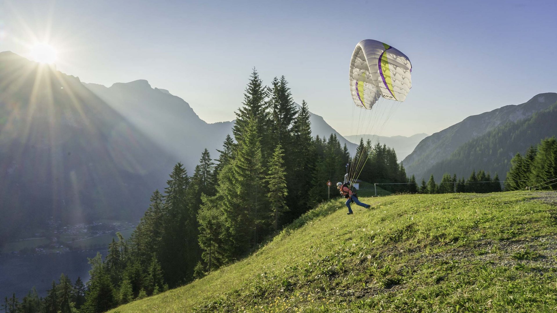 Our hotel on Lake Achensee with swimming pool Person launching paragliding flight at sunset in the mountains