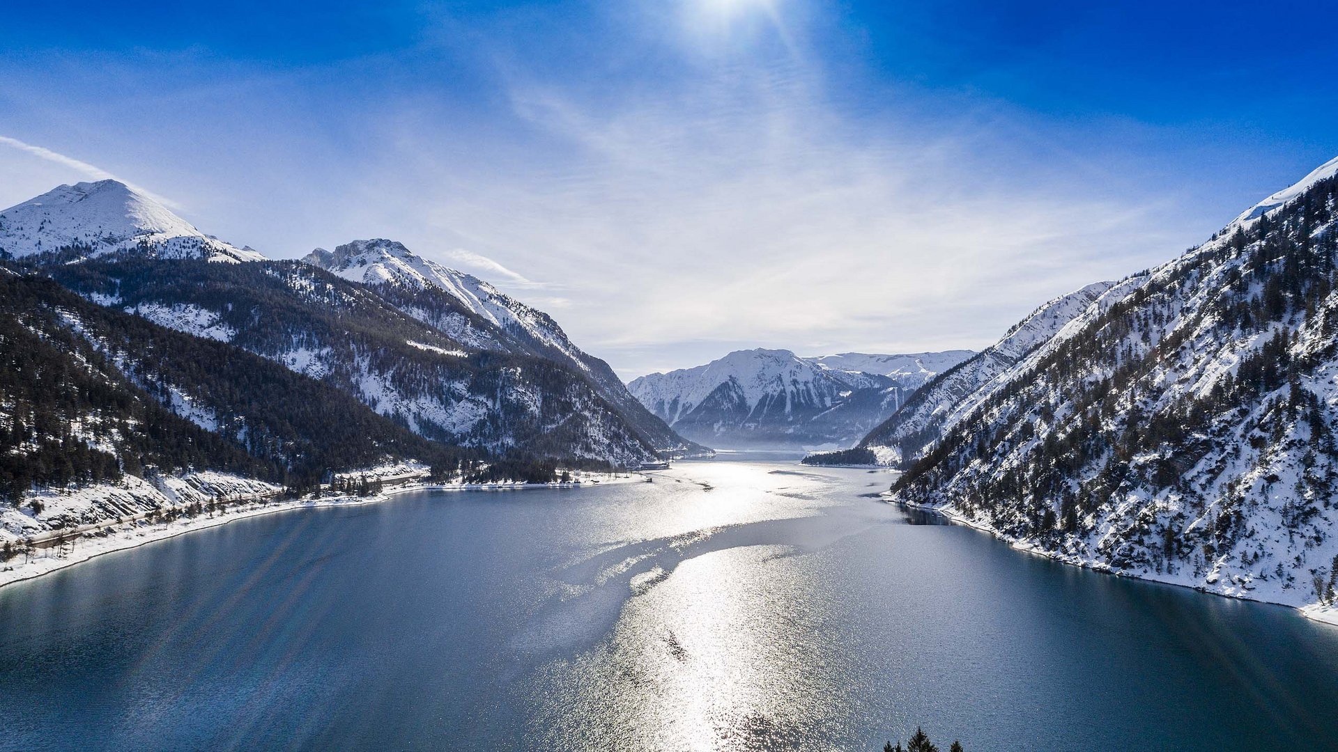 Mountain lake with snow-covered peaks and bright sunlight