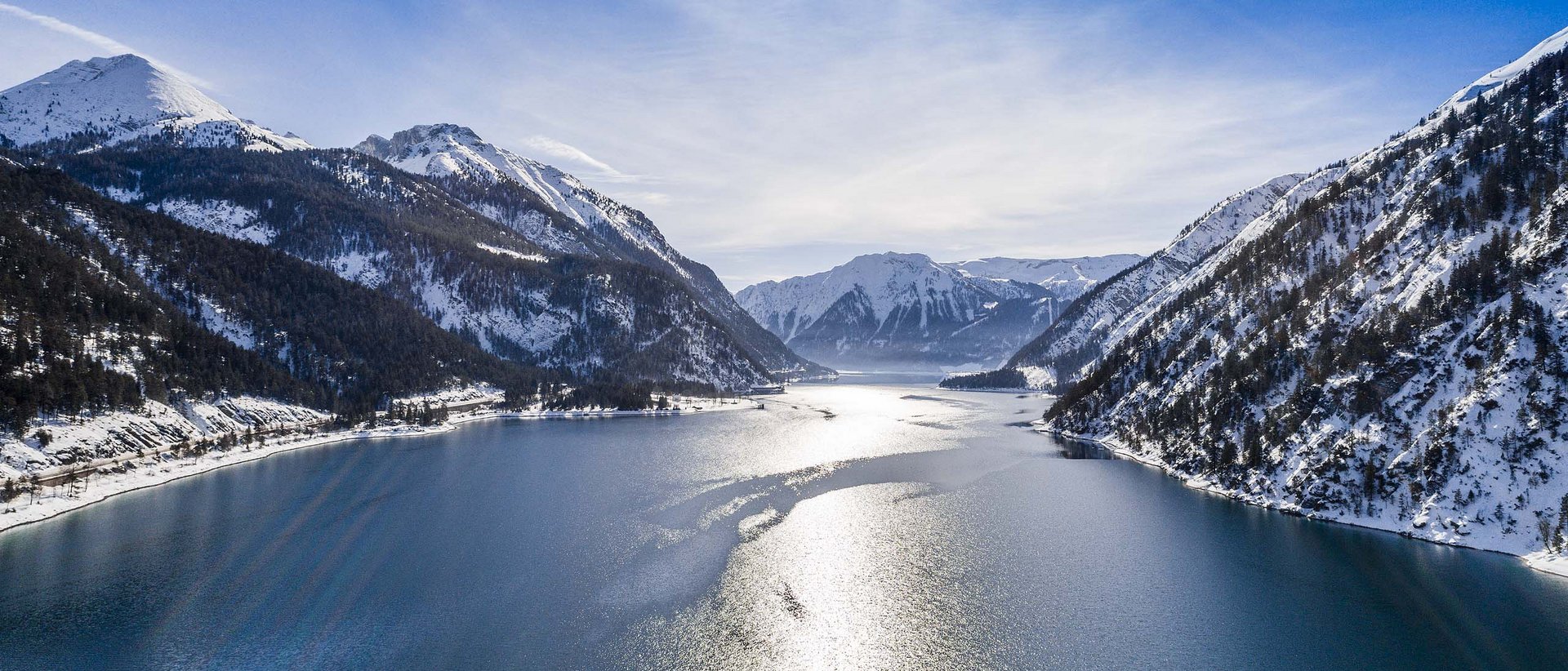 Ein Urlaubsort für jeden Geschmack Bergsee mit Schnee bedeckten Bergen und strahlendem Sonnenschein