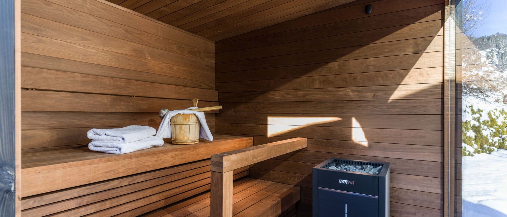 Wie Schwitzen unsere Gesundheit fördert Moderne Sauna mit Holzbanken, Handtüchern und Blick auf schneebedeckte Landschaft
