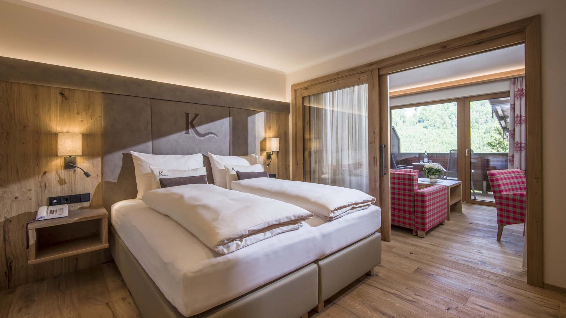 4-Sterne-Hotel am Achensee in Pertisau Gemütliches Hotelzimmer mit Doppelbett und angrenzendem Sitzbereich mit Balkonblick