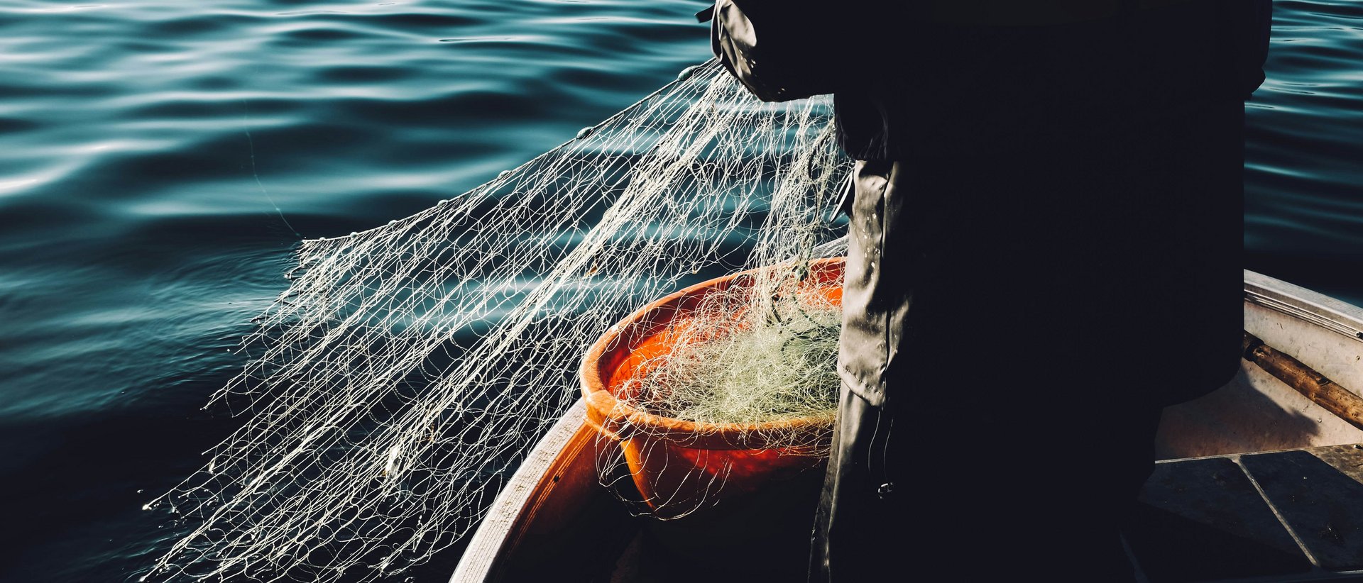 Fischen am Achensee Fischer auf Boot zieht Fischernetz aus ruhigem Wasser
