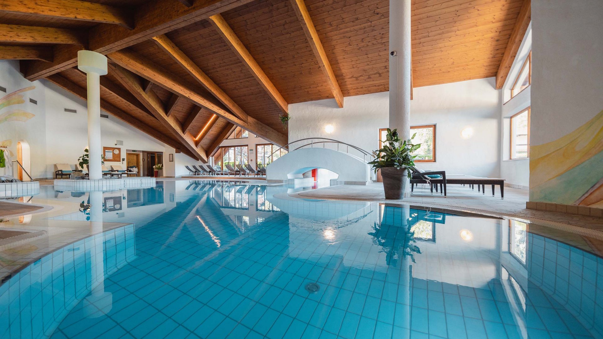 Wellnesshotel am Achensee: Karlwirt Innenaufnahmes eines Schwimmbads mit Holzdecke und Liegestühlen