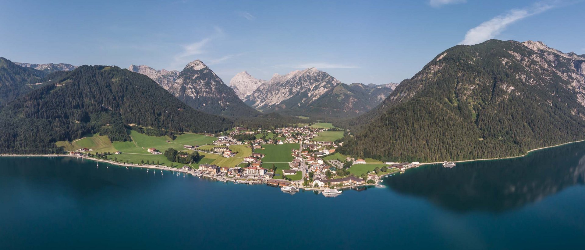 Die schönste Laufveranstaltung Österreichs Dorf am Seeufer mit Bergen im Hintergrund unter blauem Himmel