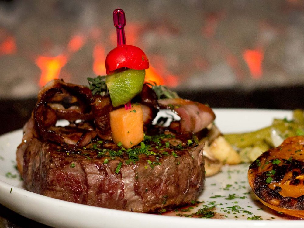 Hotel Karlwirt in Pertisau = love for the environment Grilled steak with vegetables and potato side on white plate with Karlwirt flag
