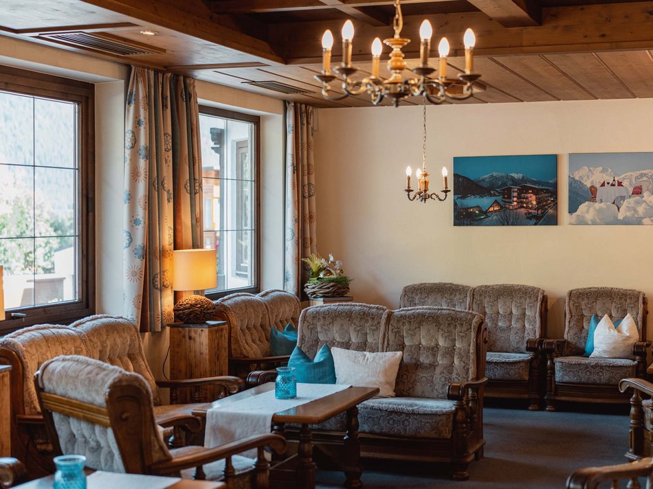Das Hotel Karlwirt: herzlich willkommen! Gemütlicher Aufenthaltsraum mit Holzmöbeln und Bergblick durch die Fenster