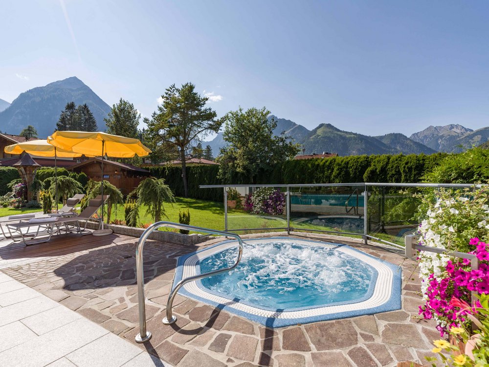 Wellnesshotel am Achensee: Karlwirt Whirlpool mit Bergblick, Liegestühlen und Sonnenschirmen im Garten