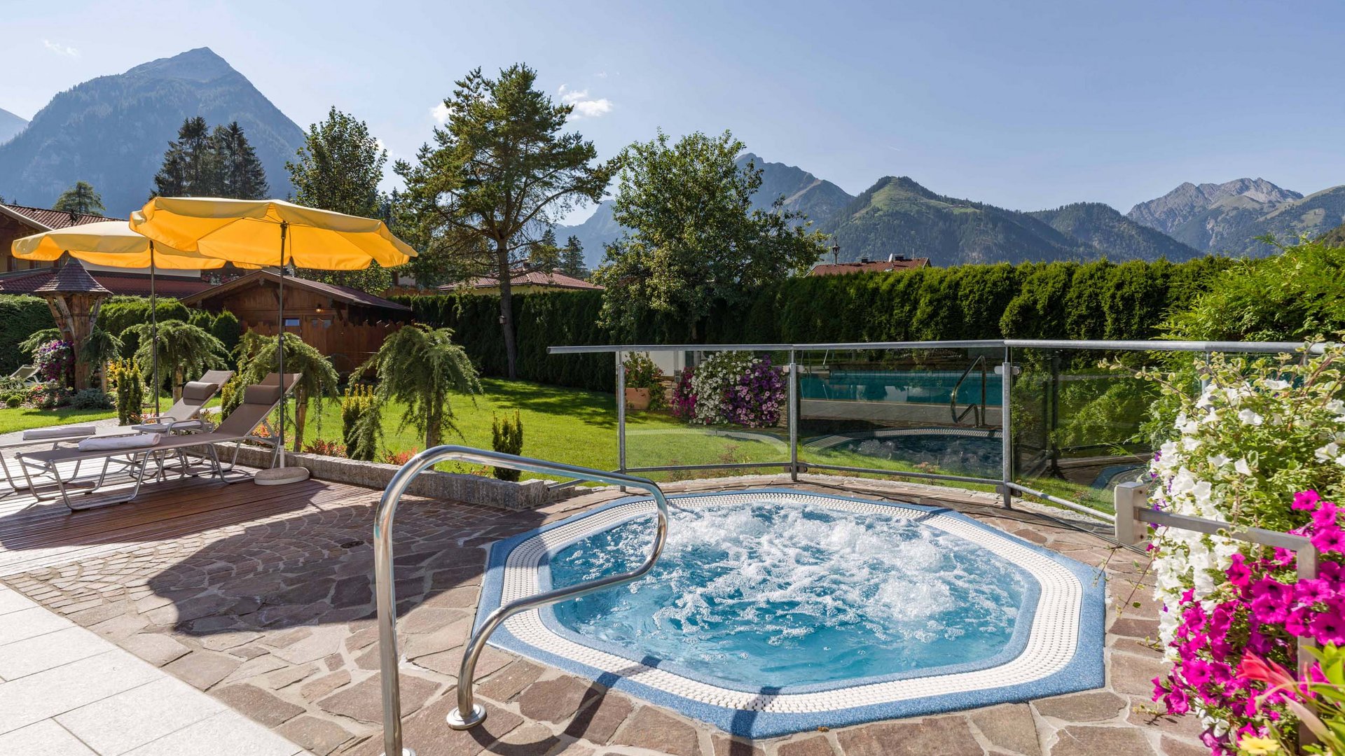 Achensee + Hotel mit Pool = Karlwirt Whirlpool mit Bergblick, Liegestühlen und Sonnenschirmen im Garten