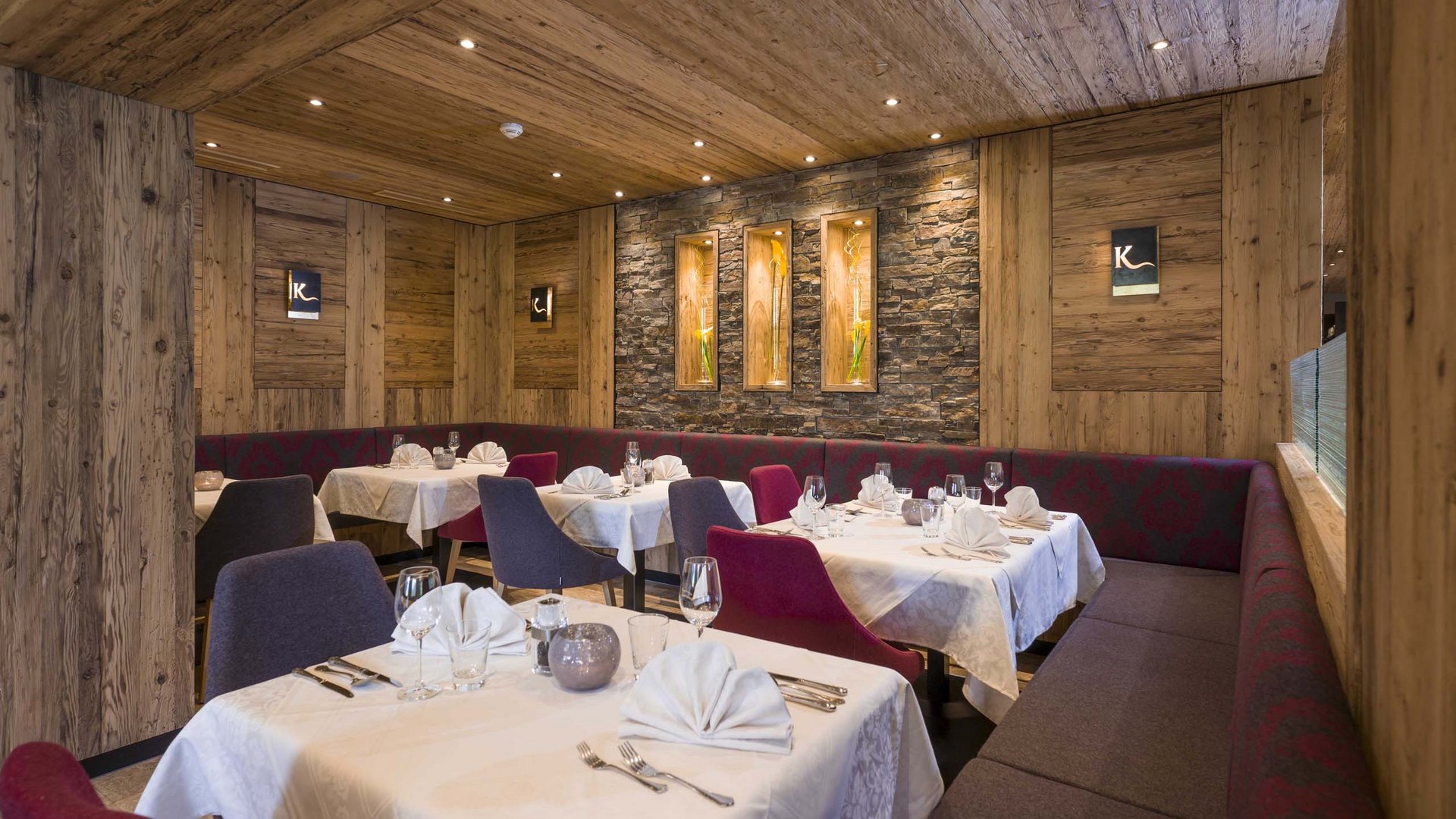Hotel on Lake Achensee? The Karlwirt! Elegant restaurant with wooden walls, set tables and modern decor