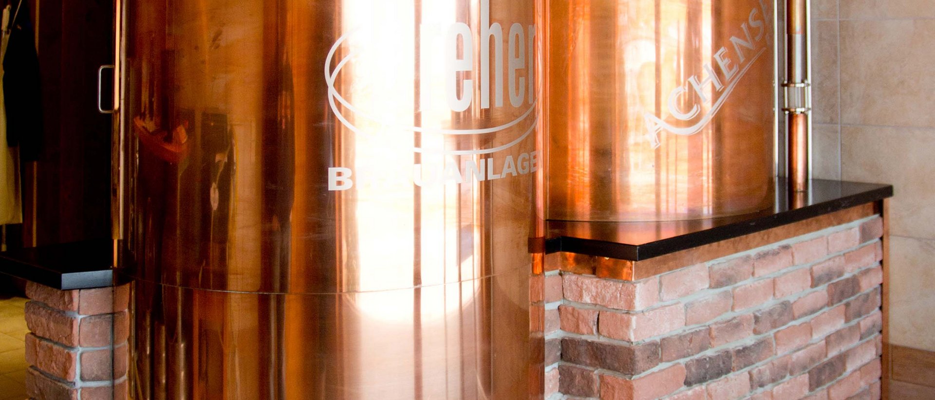 So funktioniert’s. Kupferne Bierbrauanlage in einem Raum mit Holzdach und Steinverkleidung