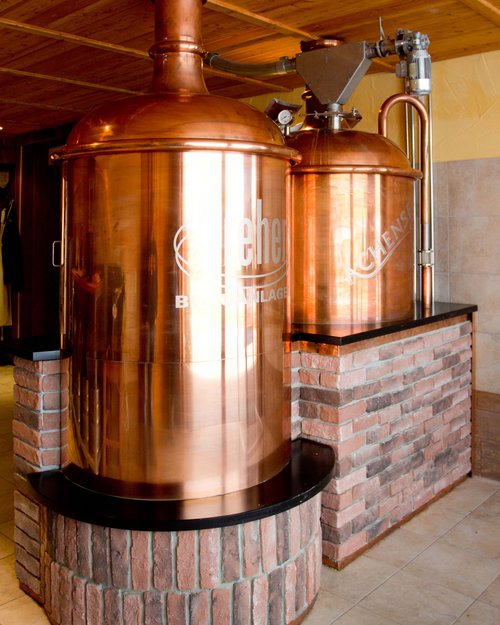 Das Restaurant am Achensee: Karlwirt Kupferne Bierbrauanlage in einem Raum mit Holzdach und Steinverkleidung