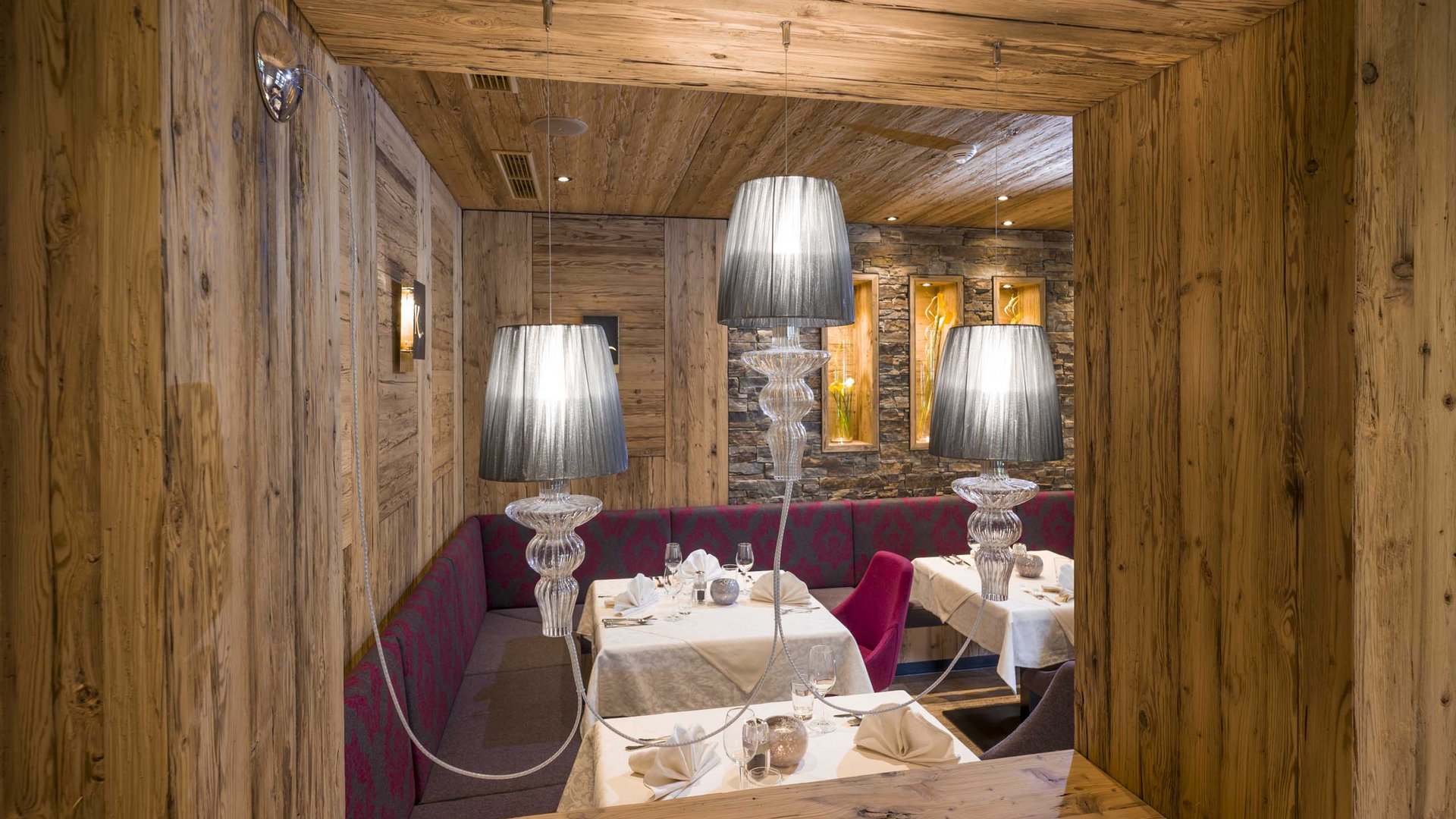 Achensee + Hotel mit Pool = Karlwirt Gemütlicher Restaurantbereich mit Holzwänden und gedeckten Tischen mit Lampen