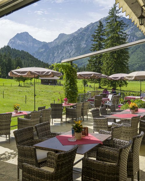 Hotel on Lake Achensee? The Karlwirt! Terrace with tables and chairs overlooking mountains, meadows, and trees