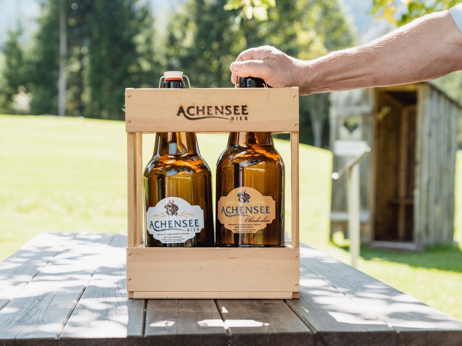 Das Achenseebier des Karlwirt Zwei Flaschen Achensee Bier in einem Holzträger auf einem Holztisch im Freien