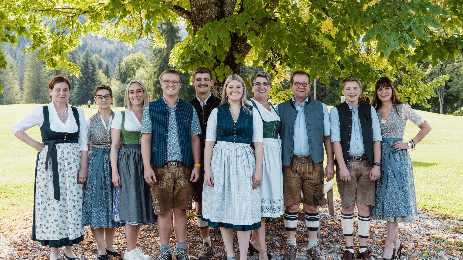Die Karlwirt-Crew Gruppe von Menschen in traditioneller bayerischer Tracht im Freien unter einem Baum