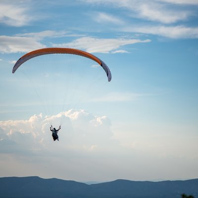 Das Hotel Karlwirt: herzlich willkommen! Gleitschirmflieger vor blauem Himmel über einer Berglandschaft