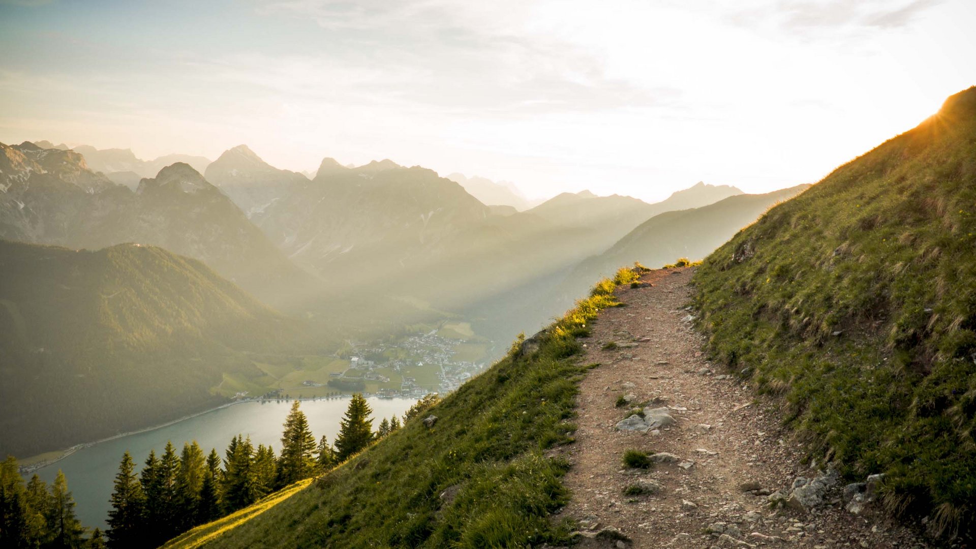 Lake Achensee: day trip options and more Mountain trail on hillside with view of valley, lake, and mountains at sunset