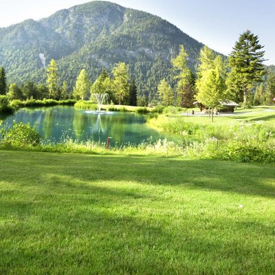 Das Hotel Karlwirt: herzlich willkommen! Frau spielt Golf auf grünem Platz mit Berg und Teich im Hintergrund
