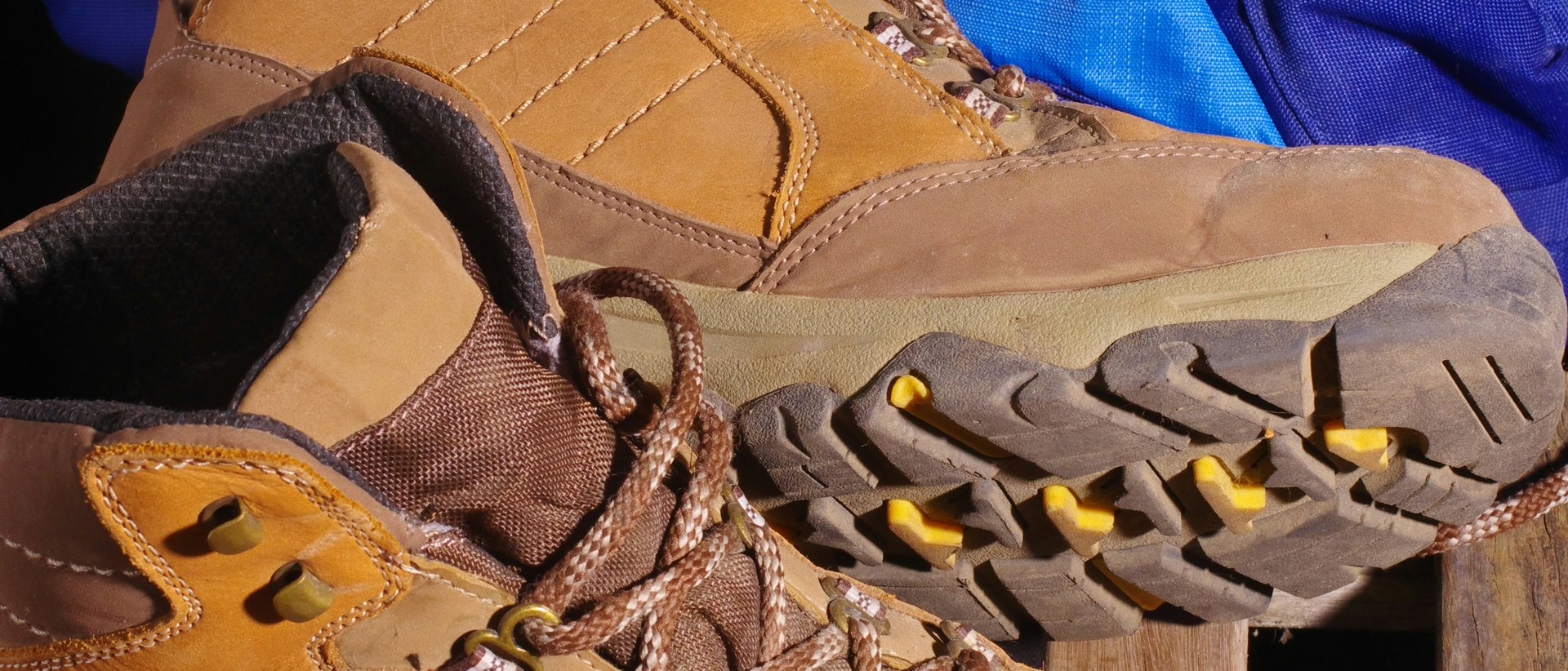 Leichte Wanderung zur Dalfazalm Braune Wanderschuhe mit blauem Rucksack auf Holzgitter