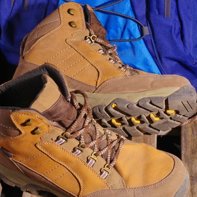 Verwöhnhotel am Achensee: Neuigkeiten Braune Wanderschuhe mit blauem Rucksack auf Holzgitter