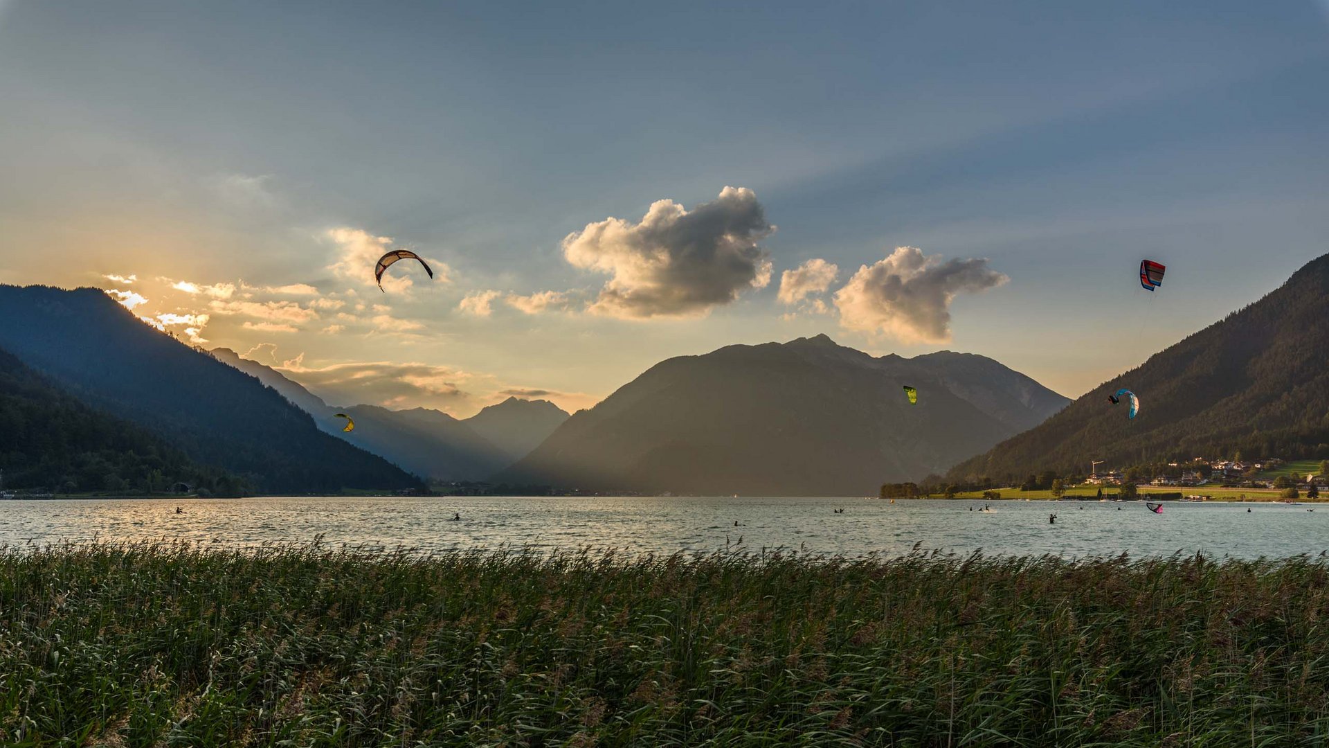 Our hotel on Lake Achensee with swimming pool Kitesurfers on a mountain lake at sunset with mountains and grass in foreground