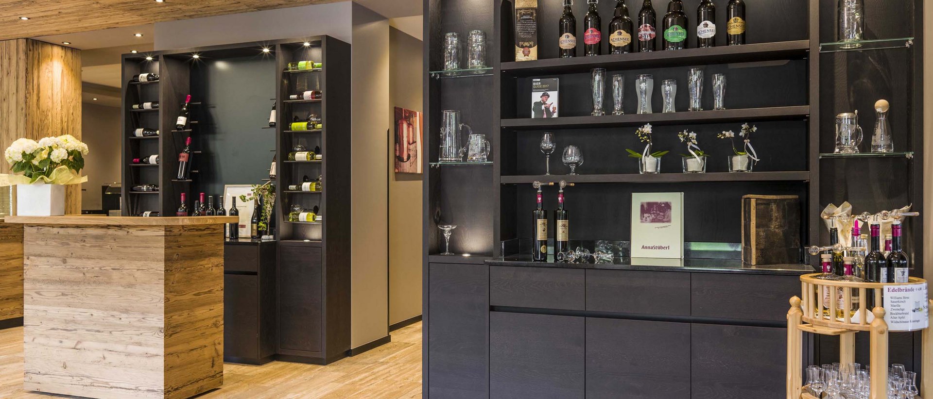 Die Brennerei Kostenzer Elegante Bar mit Holztheke und Regalen voller Flaschen und Gläser