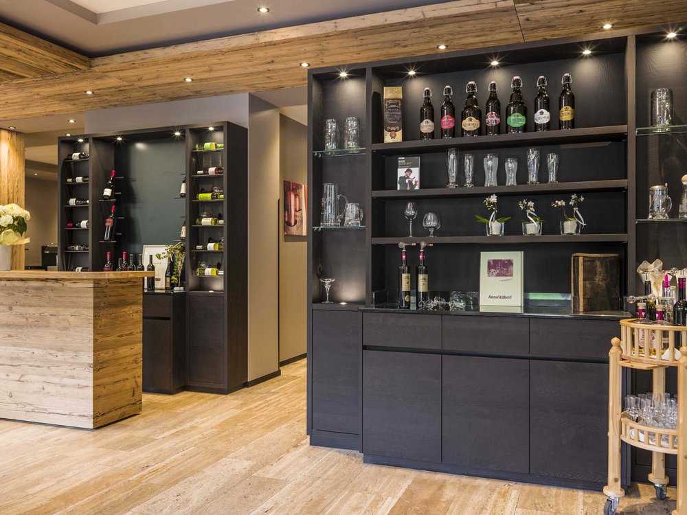 Lake Achensee + hotel with pool = Karlwirt Elegant bar area with wooden counter and shelves of bottles and glasses