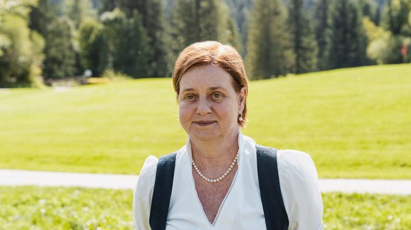 Die Karlwirt-Crew Frau in Trachtenkleidung vor grüner Wiese und Wald